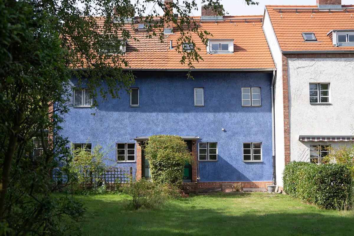 Blau verputzte Reihenhauszeile der Hufeisensiedlung in Berlin-Britz mit den originalen weißen Sprossenfenstern